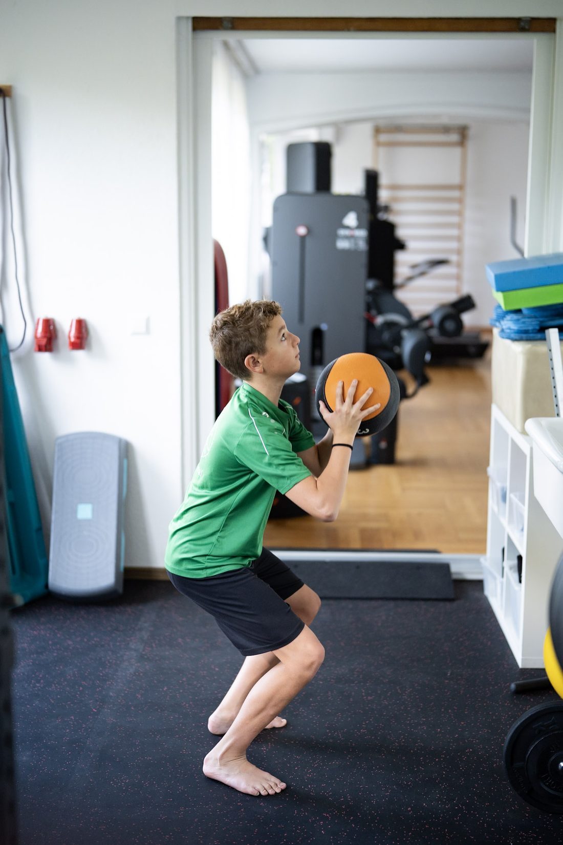 Ein Junge fängt in der Hocke einen Medizinball auf